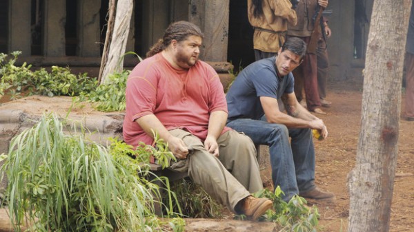 Screencap from the LOST episode "Lighthouse": Hurley and Jack sit outside the Temple, having a discussion. A few unidentified Others stand in the background