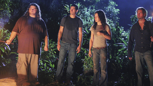 LOST Screencap. Hurley, Jack, Kate, and Sawyer (from left to right) stand in the jungle at night. Hurley holds a torch, and all of the characters look intently to their left.