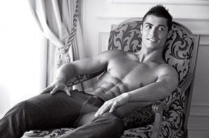Soccar star Ronaldo, sitting shirtless in a chair, smiles and looks to the right side of the frame.
