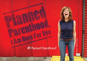 Lizz Winstead standing in front of a Planned Parenthood I Am Here For You sign