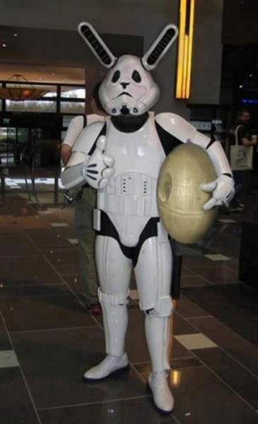 A person is wearing adapted Storm Trooper cosplay so that xe looks like a rabbit in the space armour. Xe is carrying an egg-shaped version of the Death Star.