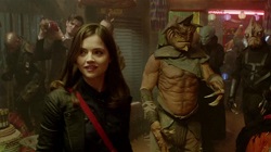 Jenna Louise Coleman as Clara Oswin Oswald stands in the middle of a crowd scene amongst aliens.