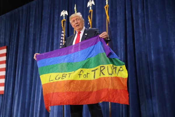Then-Republican presidential nominee Donald Trump holds a rainbow flag given to him by supporter Max Nowak during a campaign rally at the Bank of Colorado Arena on the campus of University of Northern Colorado