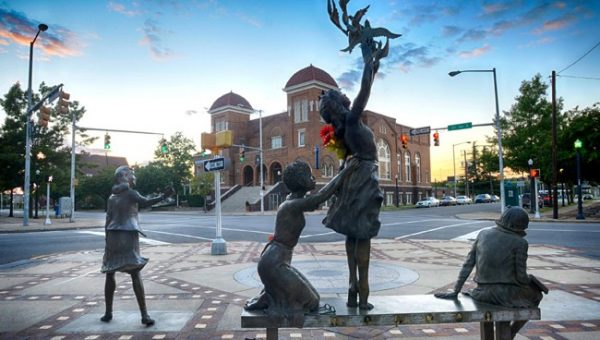 A statue of Addie Mae Collins, Carole Robertson, Cynthia Wesley, and Denise McNair, the four girls killed in the bombing of 16th Street Baptist Church, with the church in the background