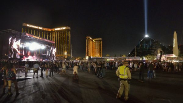 A wide shot of Vegas casinos as seen from the street, with people milling around