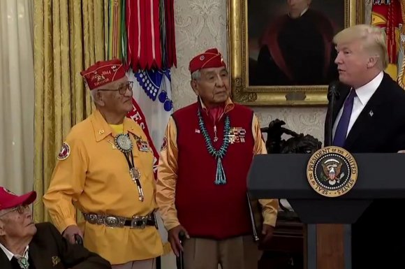 Donald Trump stands in the Oval Office, in front of a portrait of Andrew Jackson, with two Navajo code talkers for a ceremony honoring them on Monday, November 28, 2017.