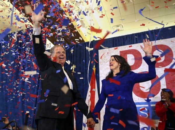 Doug and Louise Jones stand on stage amid a cloud of confetti after Doug's victory in the Alabama Senate special election Dec. 12