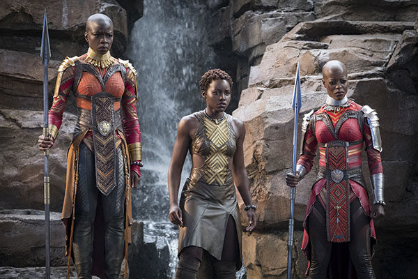 Shot from "Black Panther" of three women in African dress against a rocky background -- Florence Kasumba as Ayo, Lupita Nyong'o as Nakia, and Danai Gurira as Okoye