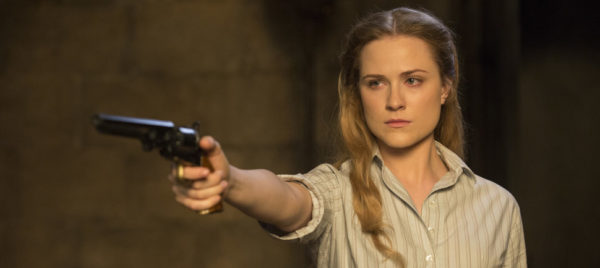Evan Rachel Woods as Dolores Abernathy in Westworld, holding a gun on an aggressor offscreen